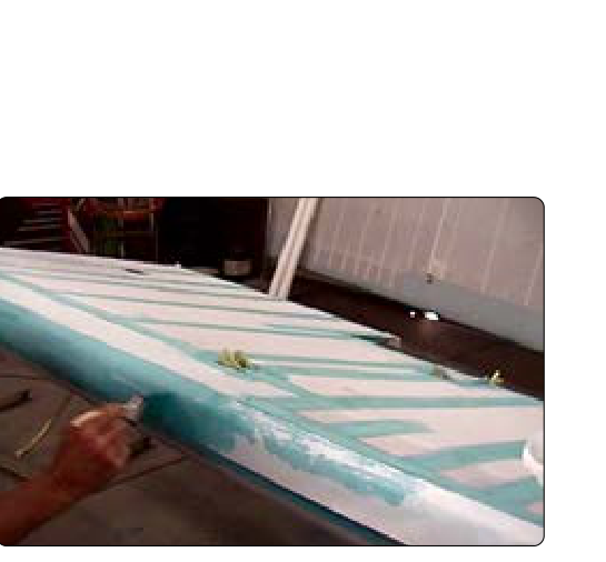 Cement is brushed through a four-inch tape during installation over the fabric seam on a wing leading edge. Two-inch tapes cover the wing ribs and rib lacing.